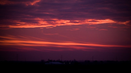 A dramatic purple pink and orange sunset with wispy clouds.