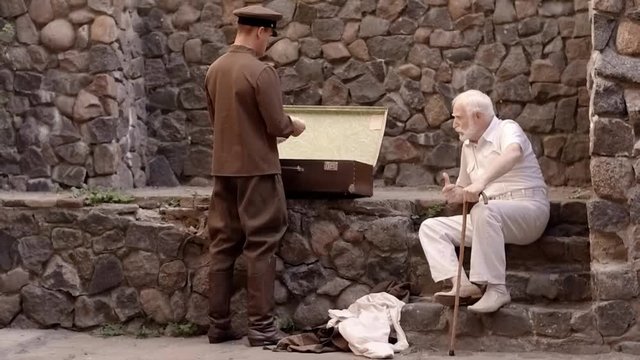 Angry NKVD soldier interrogates a miserable, bearded, gray-haired old man on the street, a soldier mocks his grandfather, tortures of the NKVD, the old man fears for his life, wartime