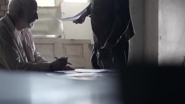Soldier of the Russian army interrogates a suspect, an elderly man with a beard, under pain of execution, signs papers, the injustice of the NKVD, cynicism of the soldiers, the cruelty of the USSR