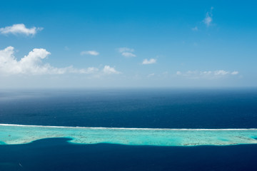 Aerial view on lagoon with blue and turquoise water, barrier reef, blue sky and white clouds of Raiatea island in French Polynesia