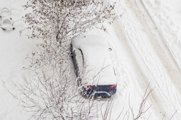 Car under the snow, view from above. Heavy snow in the city