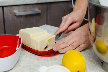 A woman is cooking in her kitchen, about to bake a cake. Woman cuts off butter for smearing...