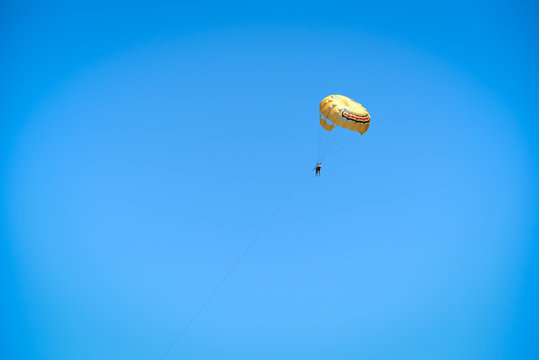 Summer sport. People flying on parachute against sky.