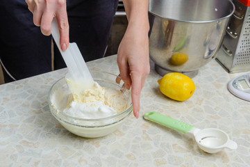 A woman is cooking in her kitchen, about to bake a cake. A woman mixes a mixture of lemon peel, chicken yolks, sugar and flour