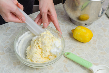 A woman is cooking in her kitchen, about to bake a cake. A woman mixes a mixture of lemon peel,...
