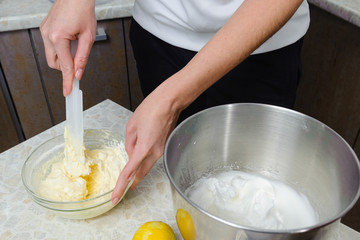 A woman is cooking in her kitchen, about to bake a cake. A woman mixes a mixture of lemon peel, chicken yolks, sugar and flour