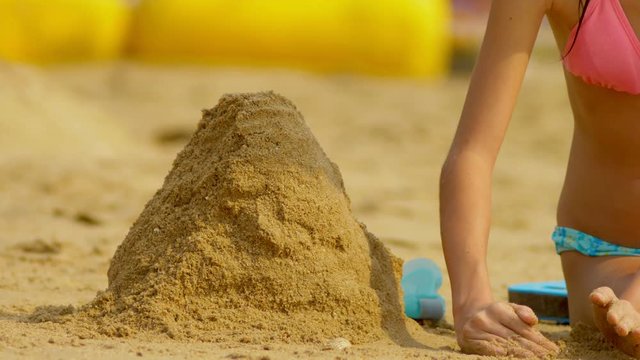 girl builds a sand castle on a tropical beach. close-up