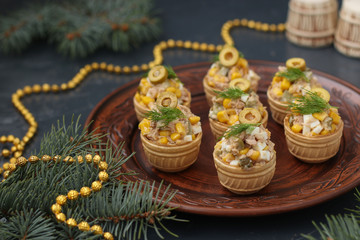 Tartlets with tuna, corn and eggs salad on a dark background