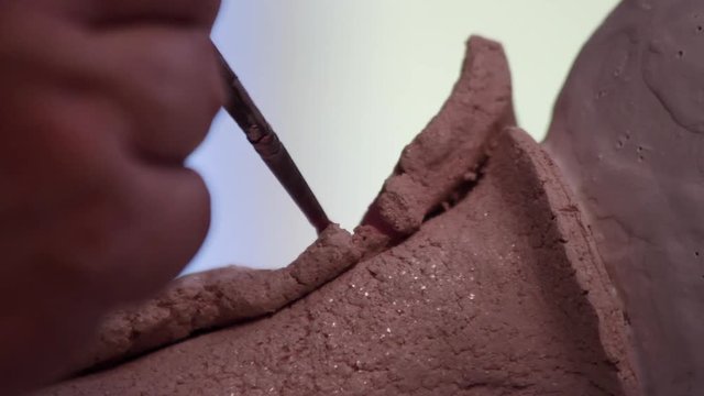 Ceramista pintando o esmaltando una pieza de cerámica