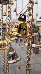 Fototapeta na wymiar Gold metal bells on a chain outside a temple in Bangkok, Thailand