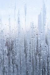 The frozen drops on the patterned frosty winter window