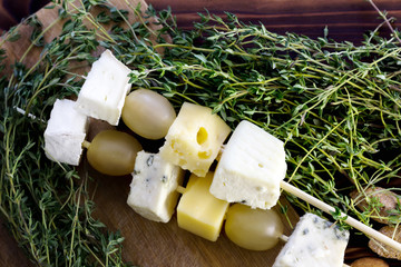 Cheese and grapes canapes on skewers.	Rustic background.