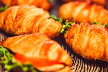 Close up fresh croissants with salad, ham and cheese on table