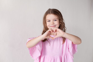 a little girl shows hands symbol heart