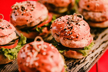 Tasty homemade mini-hamburgers on wooden board close