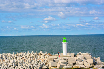 Lighthouse and levees on the sea background.