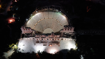 Aerial birds eye view night shot taken by drone of iconic Odeon or Amphitheater of Herodes Atticus in the slopes of Acropolis hill, Athens historic centre, Attica, Greece