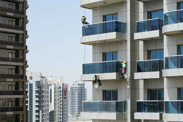 Three high-rise workers wash windows of a high-rise building in Dubai