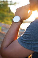 A man checks his wristwatch while on a sunny vacation to see if he needs to leave
