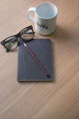 Writer's career on the desk with a white coffee mug, pencil and glasses book