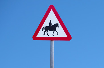 Horse pony riding beware warning sign in blue sky road animal danger of accident equestrian centre near in rural countryside
