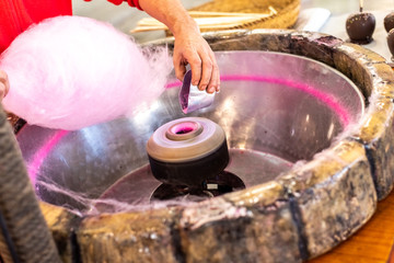 Preparation of a Candy Cotton Cloud at a fair for some children by a cook.