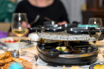 traditional swiss electric raclette stone grill unit with individual skillets on christmas table