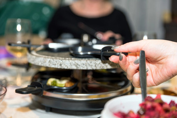 Obraz na płótnie Canvas traditional swiss electric raclette stone grill unit with individual skillets on christmas table