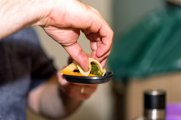 male hands preparing individual skillet for cooking in traditional swiss electric raclette stone grill