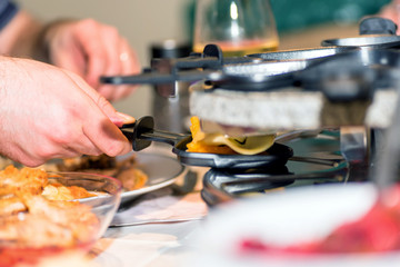 male hands preparing individual skillet for cooking in traditional swiss electric raclette stone grill