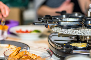 juicy yellow sweet corn on individual skillets cooking inside traditional swiss electric raclette stone grill on christmas table
