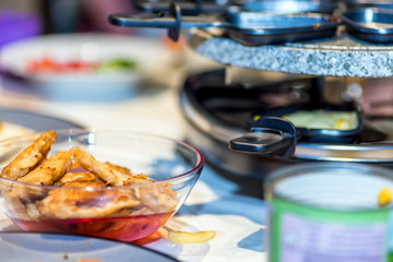 juicy yellow sweet corn on individual skillets cooking inside traditional swiss electric raclette stone grill on christmas table