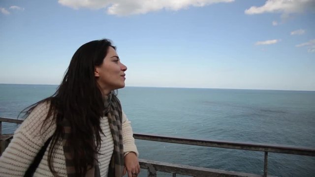 Giovane donna pensierosa su di un balcone in riva al mare