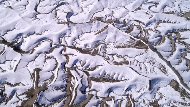Aerial view of snow covering desert landscape viewing drainage system as the water flows downstream in the Utah Badlands.