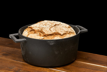 No knead or sourdough hand made bread in black cast iron pot isolated on white background including...