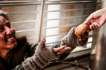 mercy hand of someone give bread to poor homeless beggar who show happy face selective focused