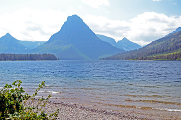 Clear lake water surrounded with mountains in Glacier National Park.