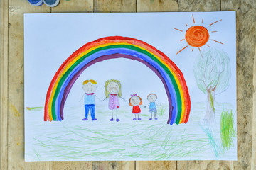 Happy family concept. Sheet with a pattern on a wooden table: parents and children hold hands against background of rainbow and sunny sky.
