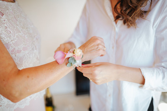 woman putting on wrist corsage for wedding