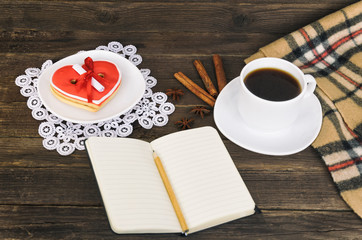 Cup of coffee, heart shaped cookies with message, notebook, pencil and checkered plaid on a brown wooden table