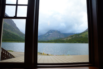 Looking through a window frame at a clear blue lake in Glacier National Park.