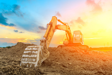 Excavator work on construction site at sunset