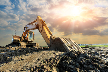 Excavator work on construction site at sunset