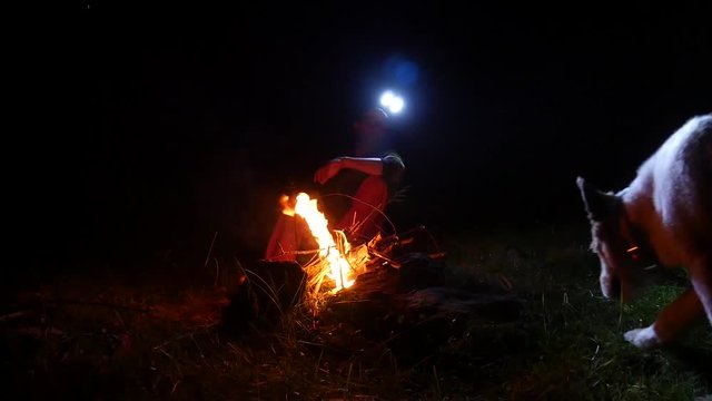 Campeggio notturno uomo e cane intorno al fuoco
