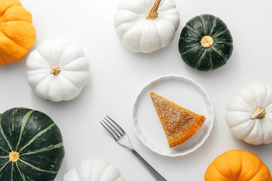 Pumpkin Pie On A White Plate With Pumpkins On A White Background, Homemade Autumn Food For Thanksgiving Concept