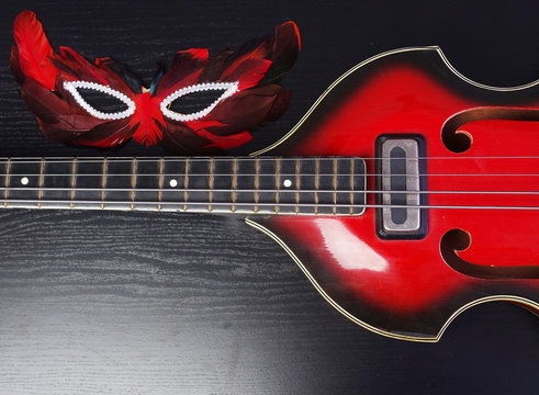Electro bass guitar and carnival mask on a dark background