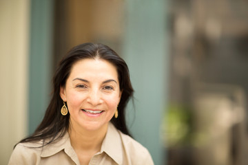 Happy Hispanic woman smiling and standing outside.