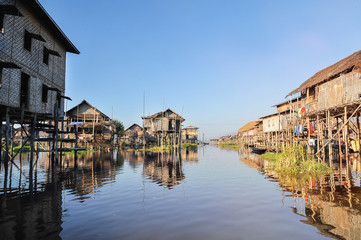 Fototapeta na wymiar Bamboo houses on piles standing in water in township