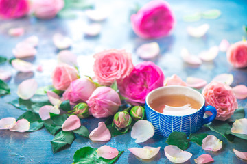 Obraz na płótnie Canvas Rose tea photography with ceramic teacups and flower petals on a wet light background with copy space. Seasonal header with drink