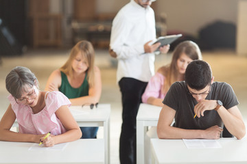 Fototapeta na wymiar Young students having exam in classroom